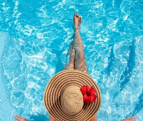 Woman with straw hat with red flower sitting in pool at Ocean City Fontainebleau Resort in Ocean City, MD