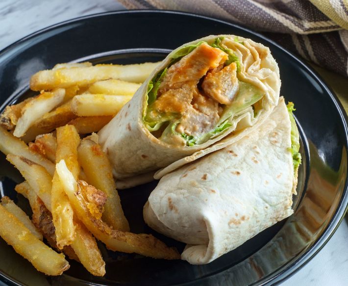 White wrap with chicken and lettuce with french fries on black plate at Ocean City Fontainebleau Resort in Ocean City, MD