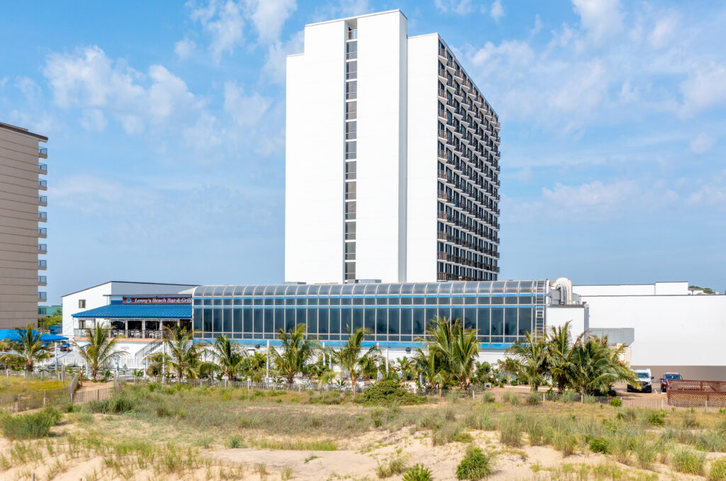 Exterior of Ocean City Fontainebleau Resort in Ocean City, MD near palm trees and sandy dunes and beach