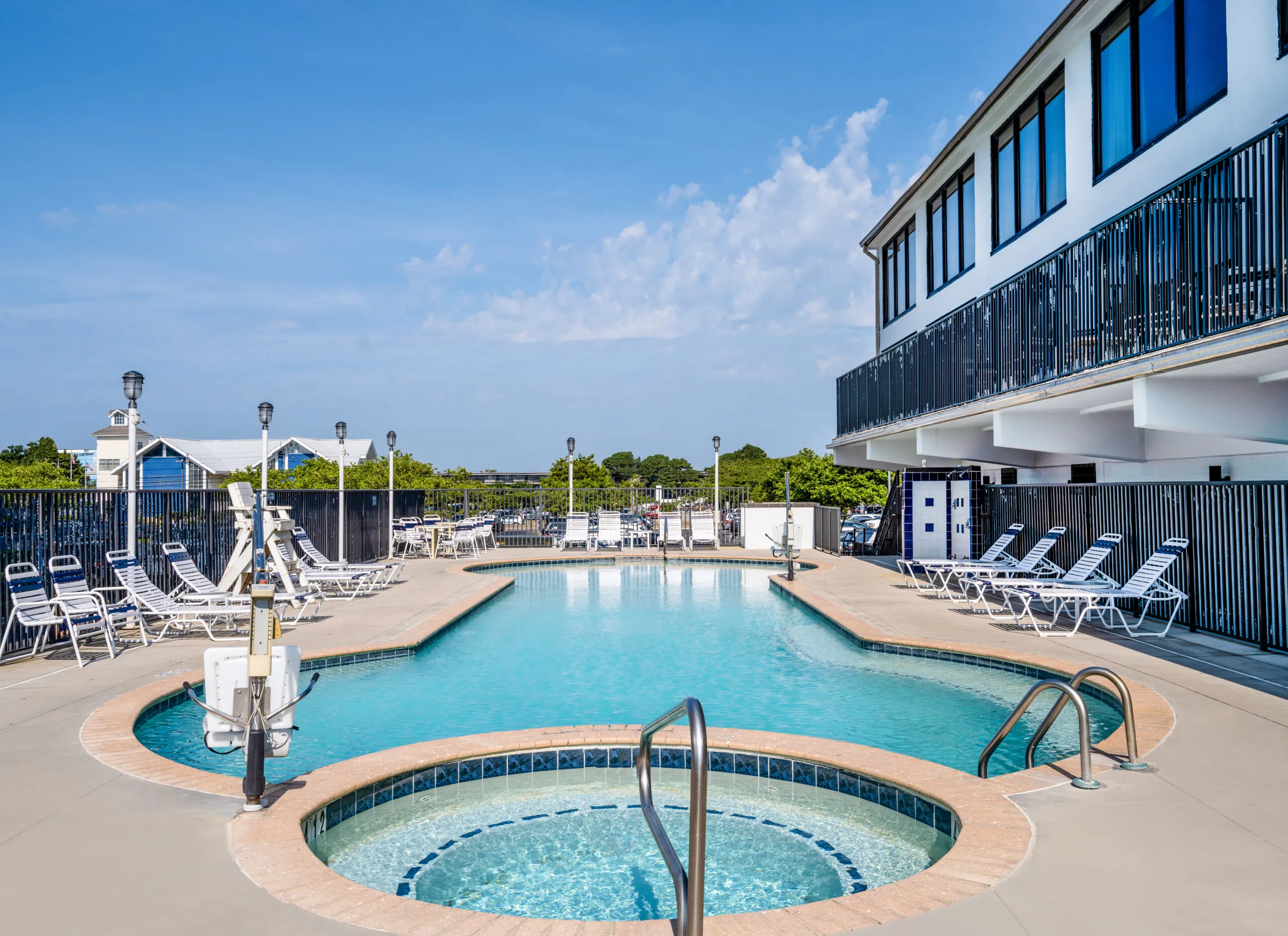 Outdoor pool with hot tub under balcony with white lounged chairs around it at Ocean City Fontainebleau Resort in Ocean City, MD